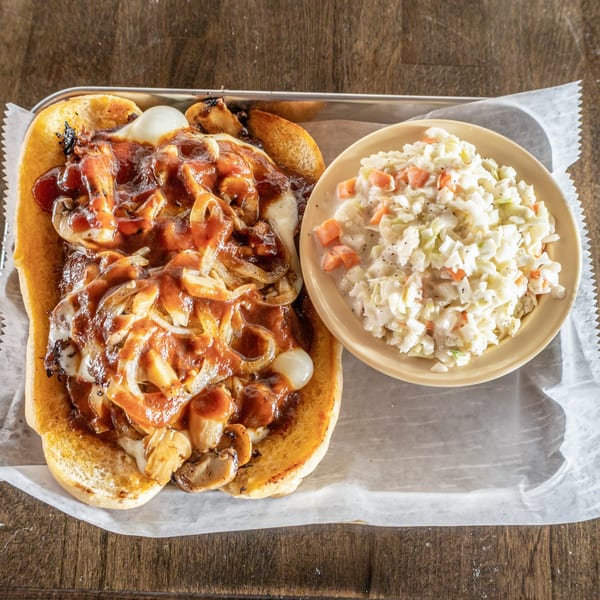 A southern BBQ cheesesteak with onions and mushrooms, served with a side of coleslaw.